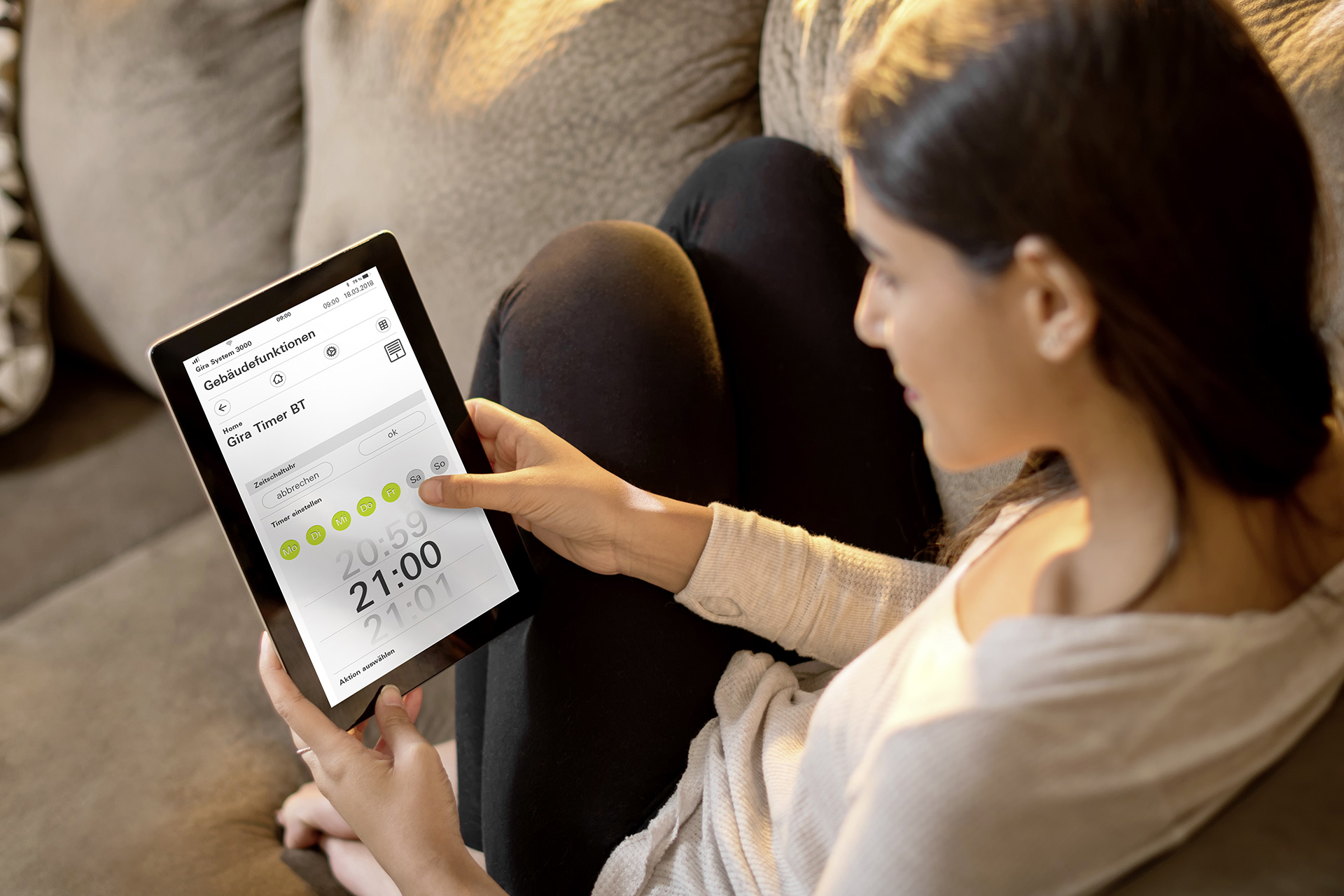Frau Steuert Smart Home mit Tablet vom Sofa aus